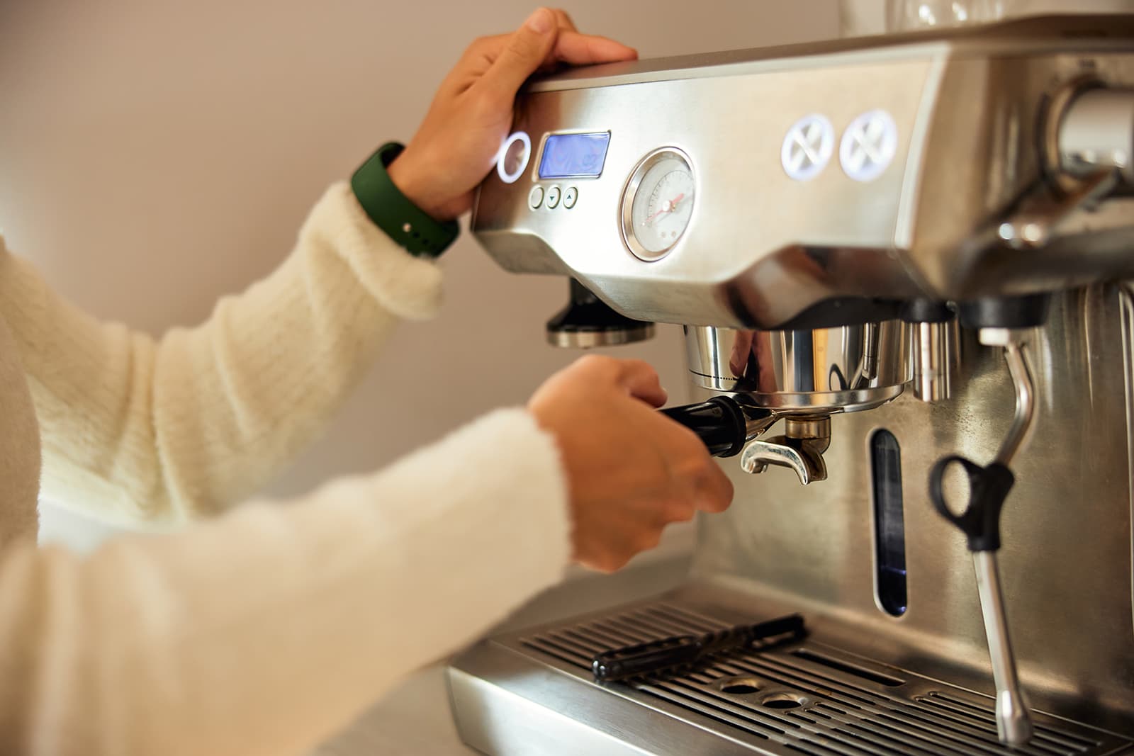 Hands operating an espresso machine — a customer enjoying a quality purchase